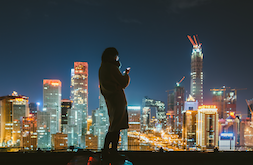 A woman using her smartphone against the Beijing skyline serves as a  reminder of opportunities for continued growth in China’s semiconductor industry.